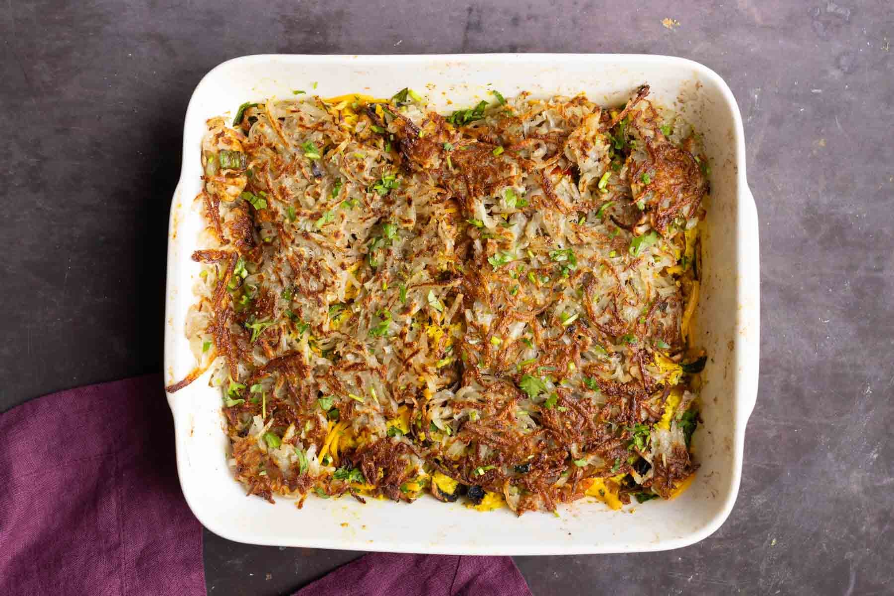 topping the vegan breakfast casserole with hashbrowns