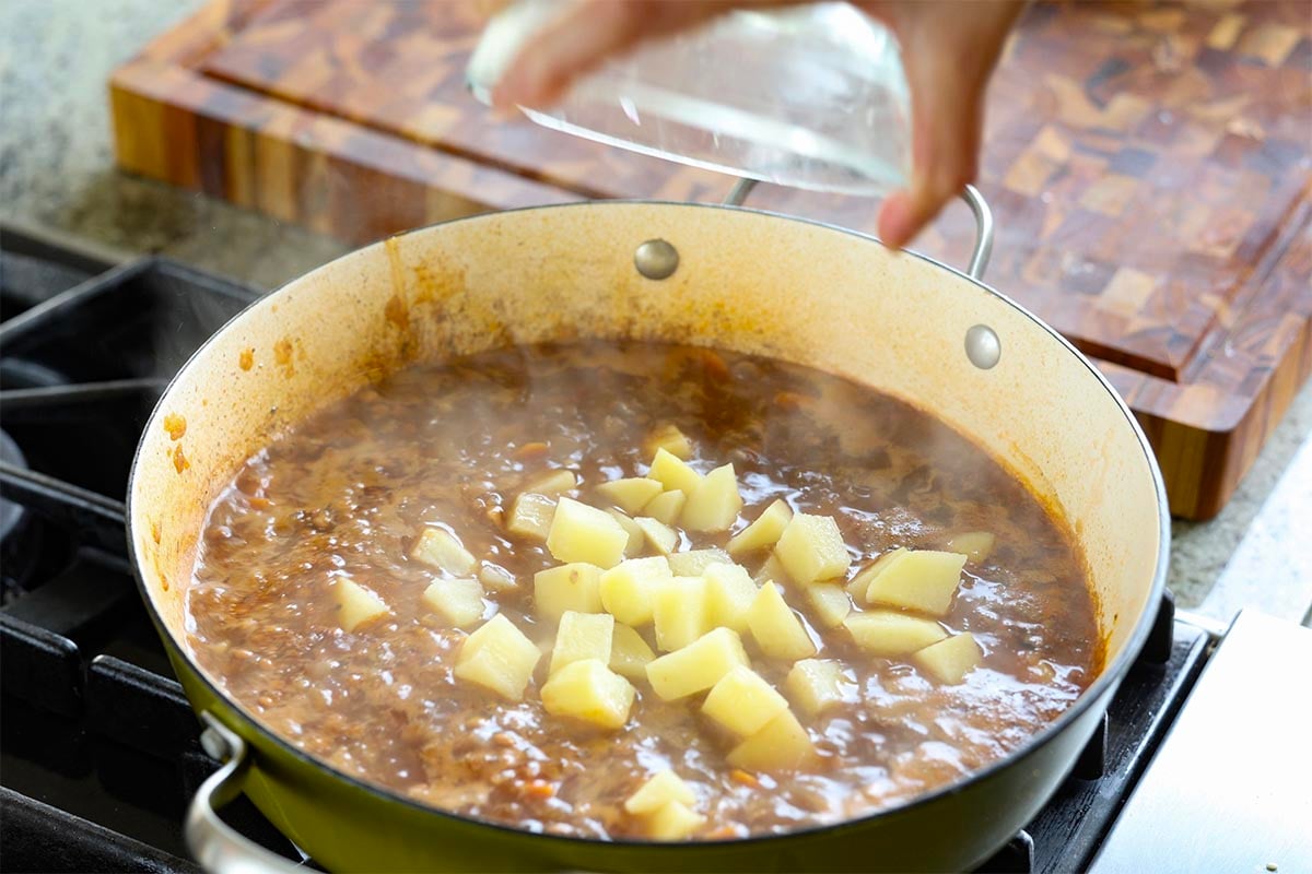 adding potatoes to the pan