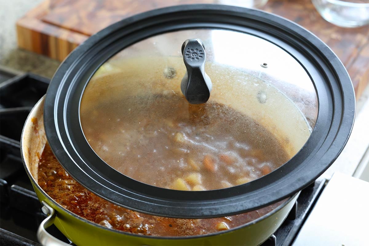 covering the pan with the lid to cook the potatoes