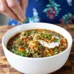 sprinkling cilantro onto the lentil potato soup