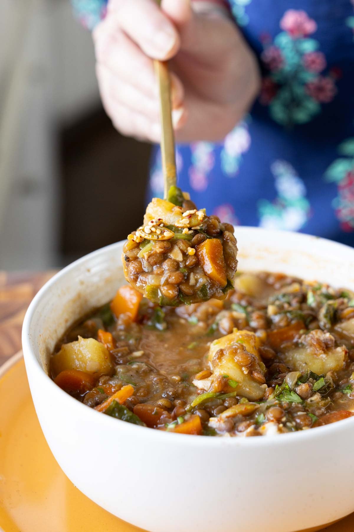 close-up of a spoon taking a bite of lentil potato soup