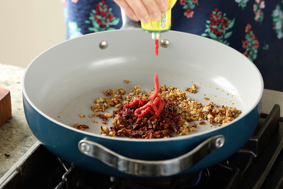 adding sun dried tomato and tomato paste to the pan