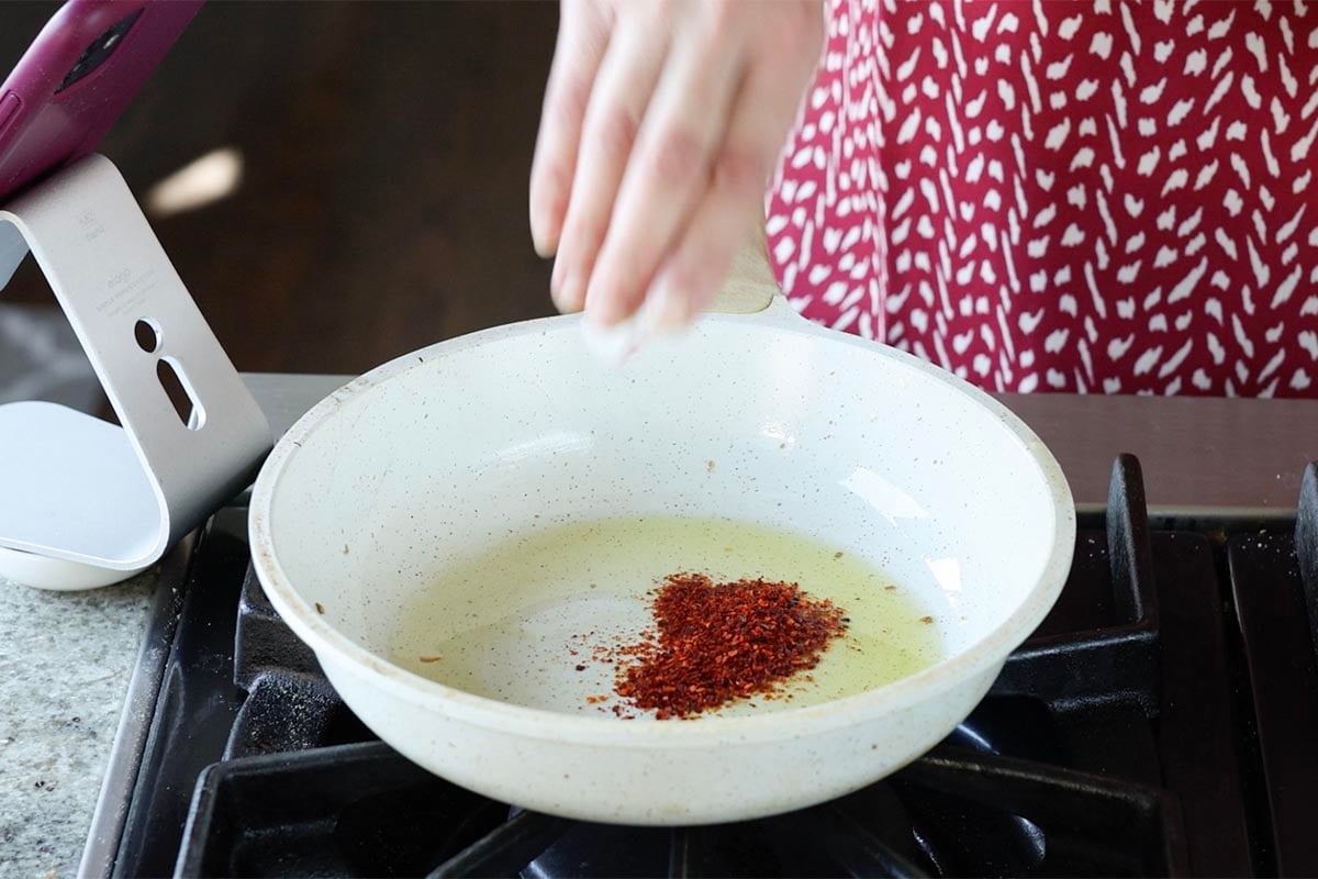 adding pepper flakes to the pan