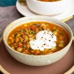 bowl of Moroccan harira garnished with yogurt and red pepper