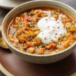 bowl of Moroccan harira garnished with yogurt and red pepper